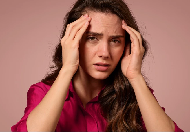 Frau fasst sich mit beiden Händen an die Schläfen