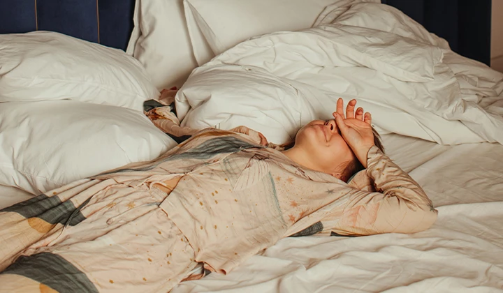 Frau liegt mit Migräne in Bett