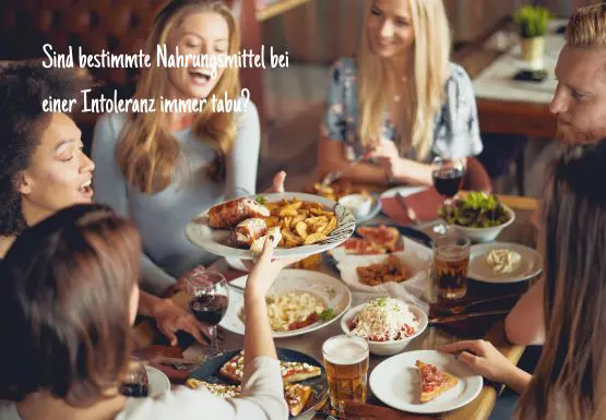 Freundesgruppe sitzt mit viel Essen um einen Tisch