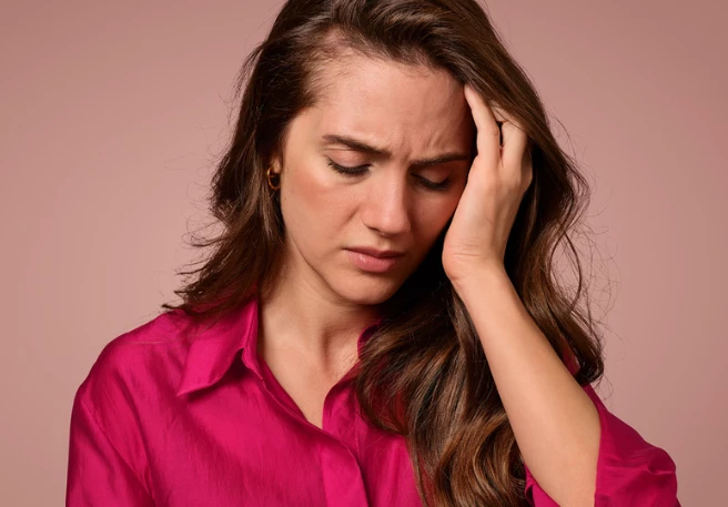 Frau fasst sich an die Schläfe